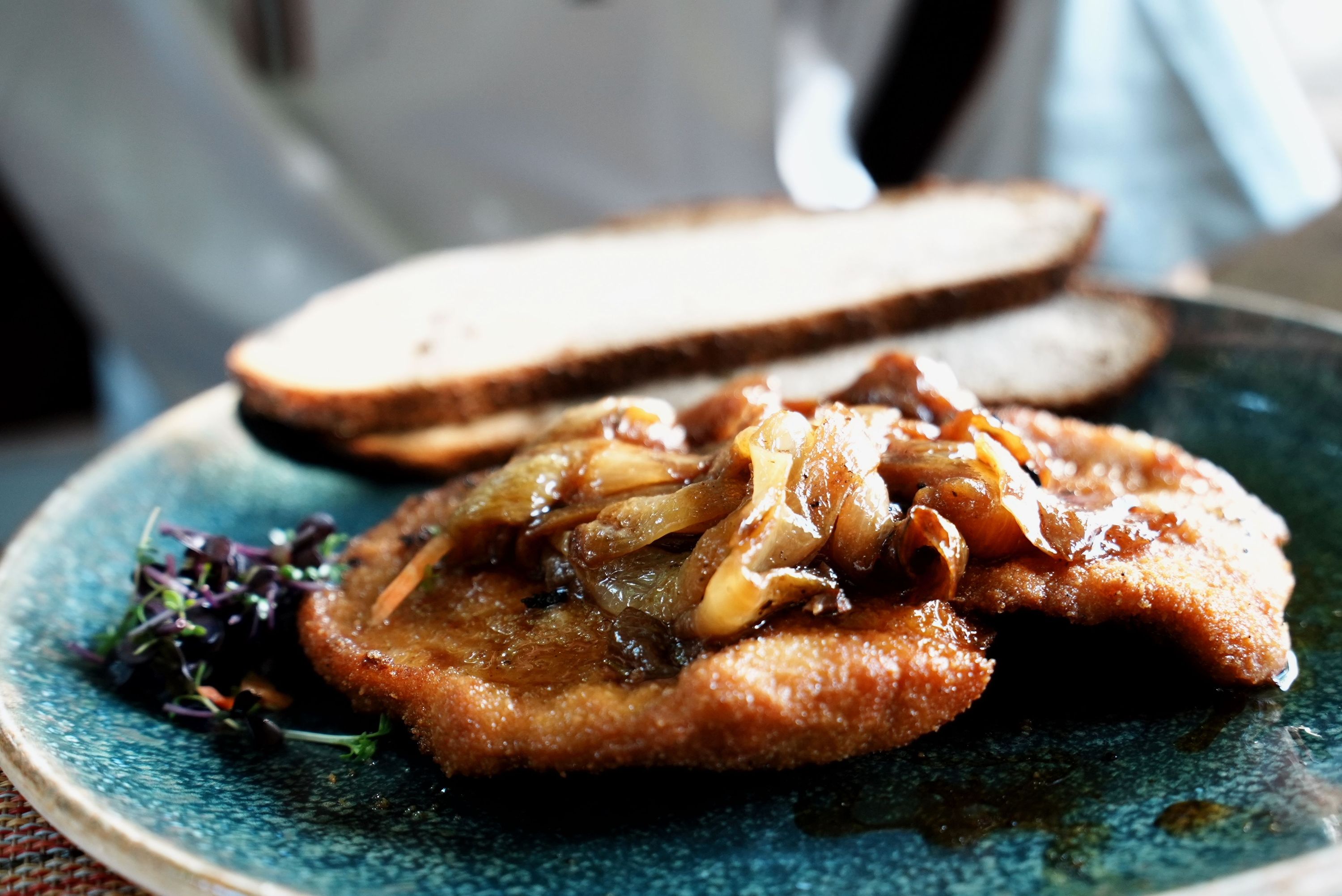 Golden fried schnitzel topped with caramelized onions, served with dark bread