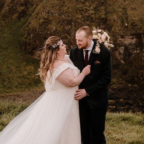 Bride and groom romantically looking at each other in an outdoor setting with cliff rocks in the background during their elopement in Ireland