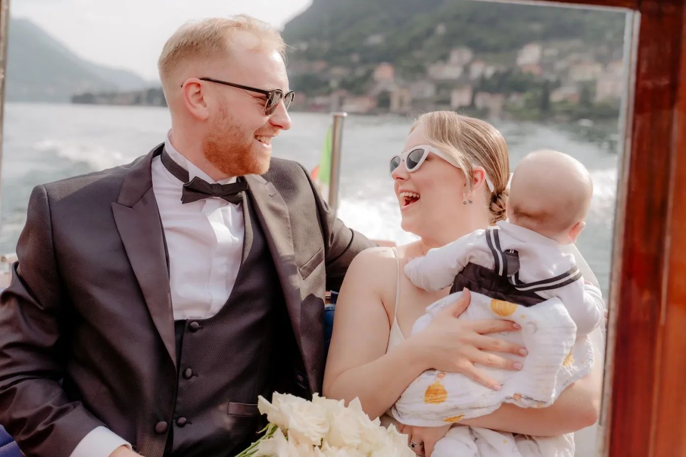 Bride and groom with their son on a boat sailing along Lake Como during their elopement in Italy