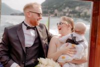 Bride and groom with their son on a boat sailing along Lake Como during their elopement in Italy
