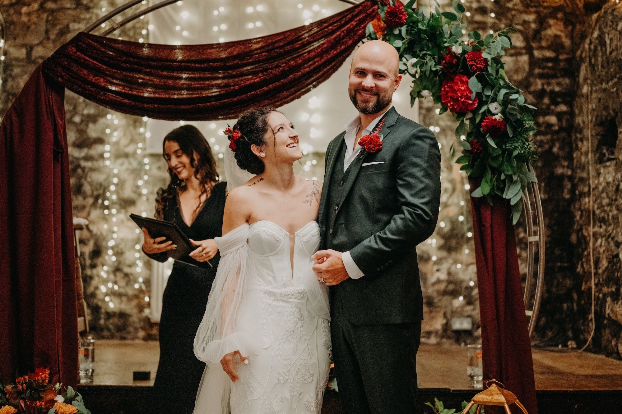 Bride and groom are in front of their guests with their wedding arch in the background during the ceremony of their micro wedding in Ireland