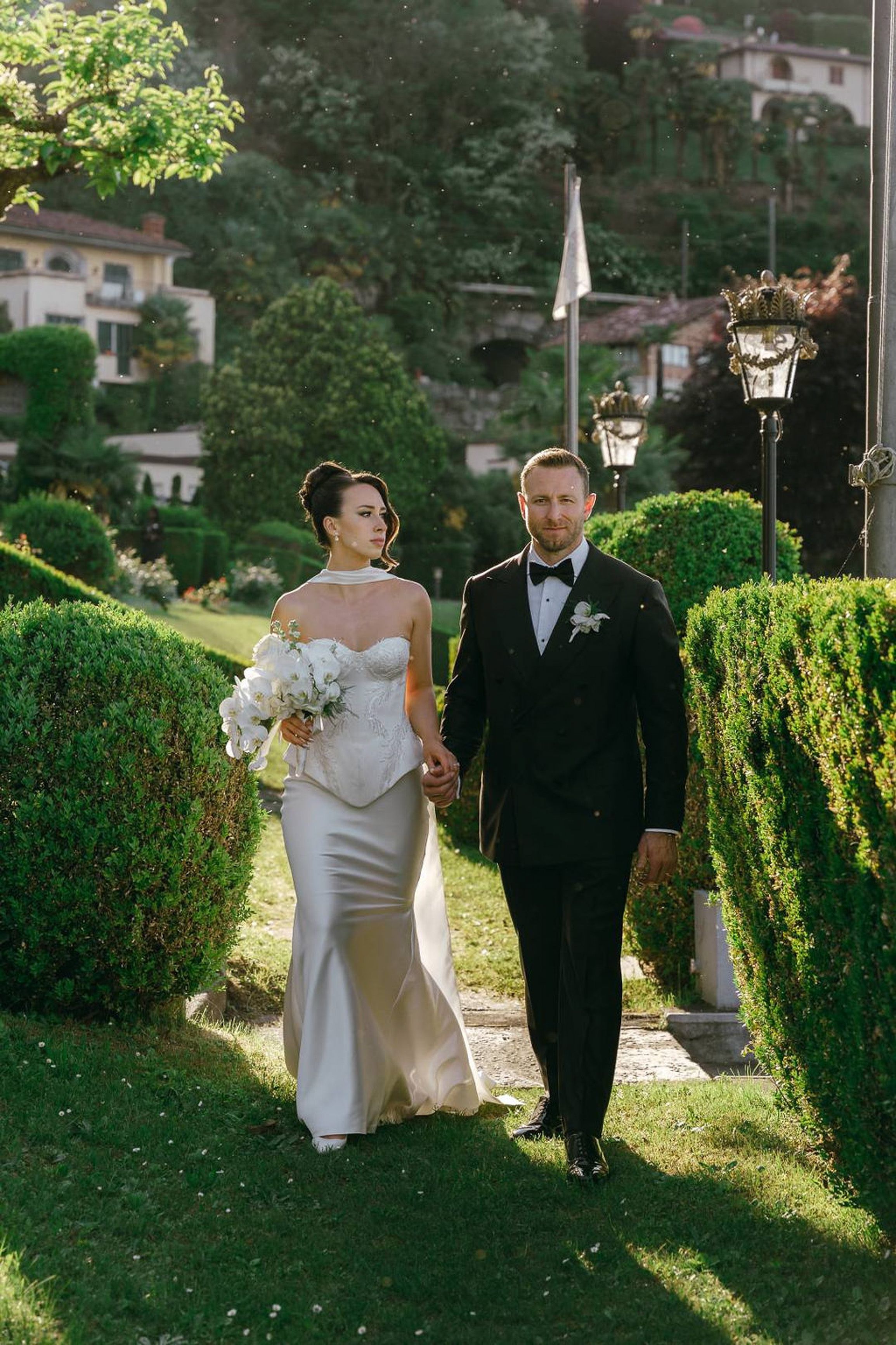 Bride and groom walking hand in hand through formal gardens at an intimate wedding in Italy