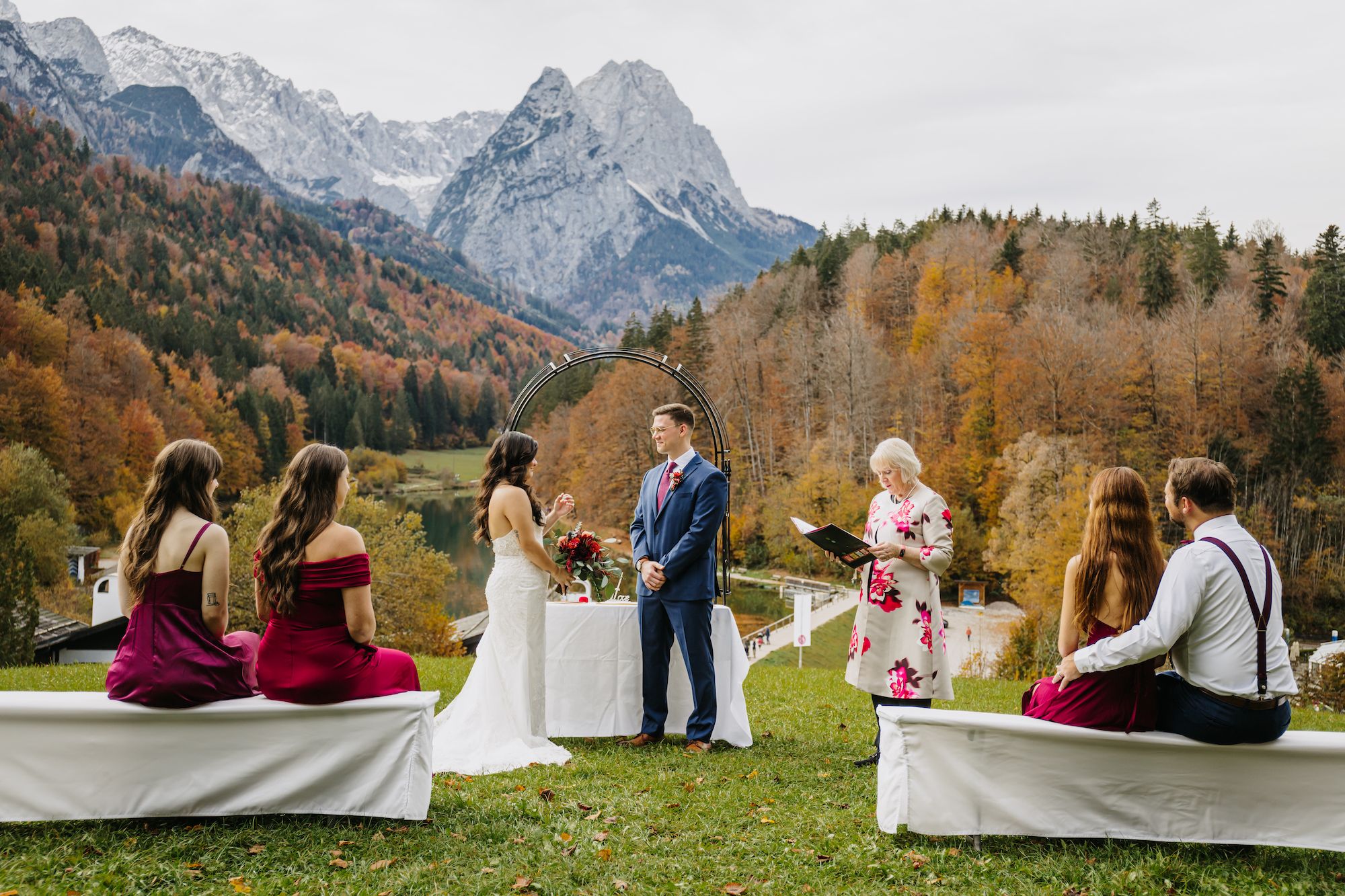 Couple having a wedding ceremony in front of a small group with Alps in the background