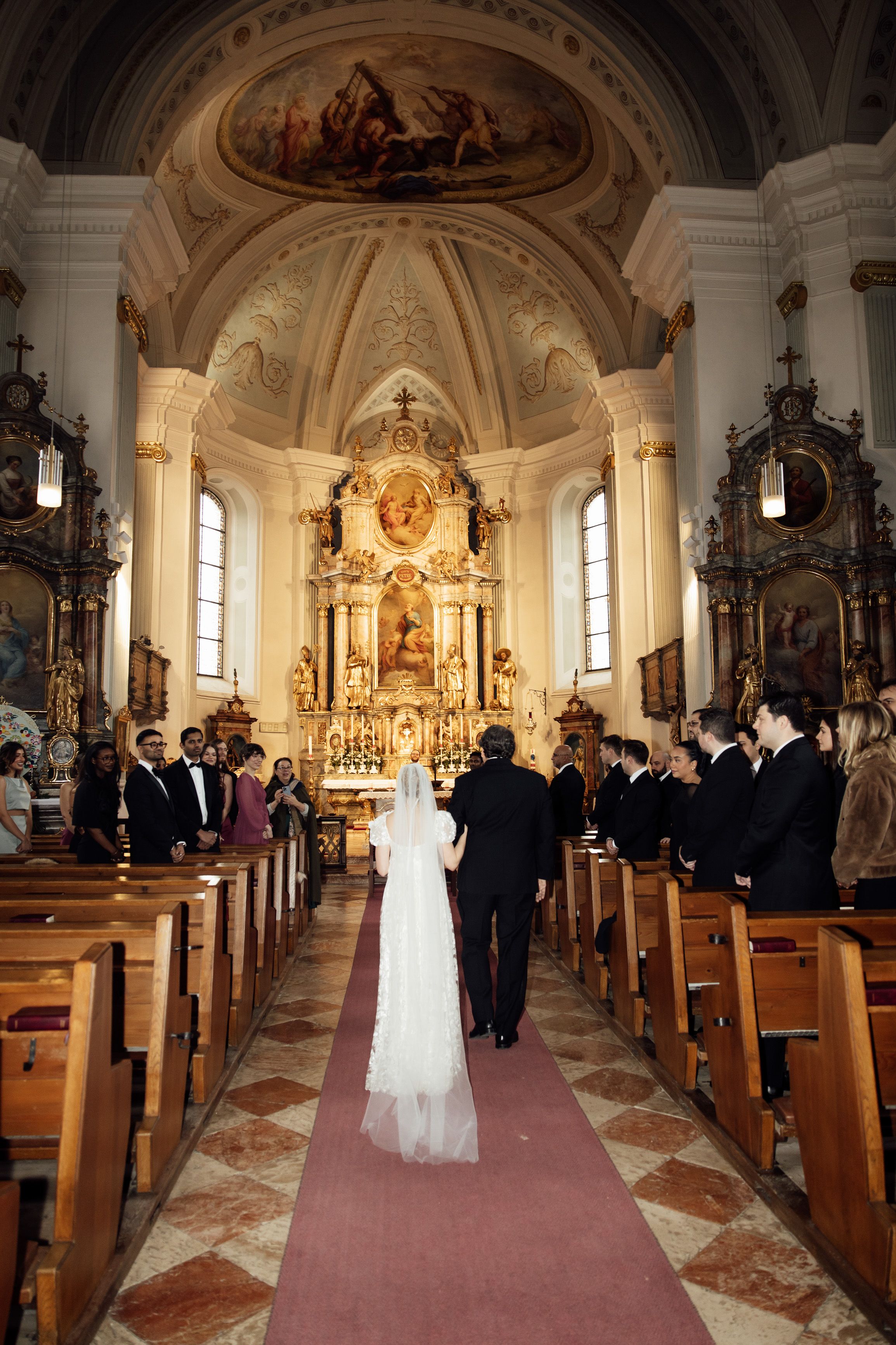 Bride walks down the aisle in a grand church during a small wedding in Austria surrounded by family and friends