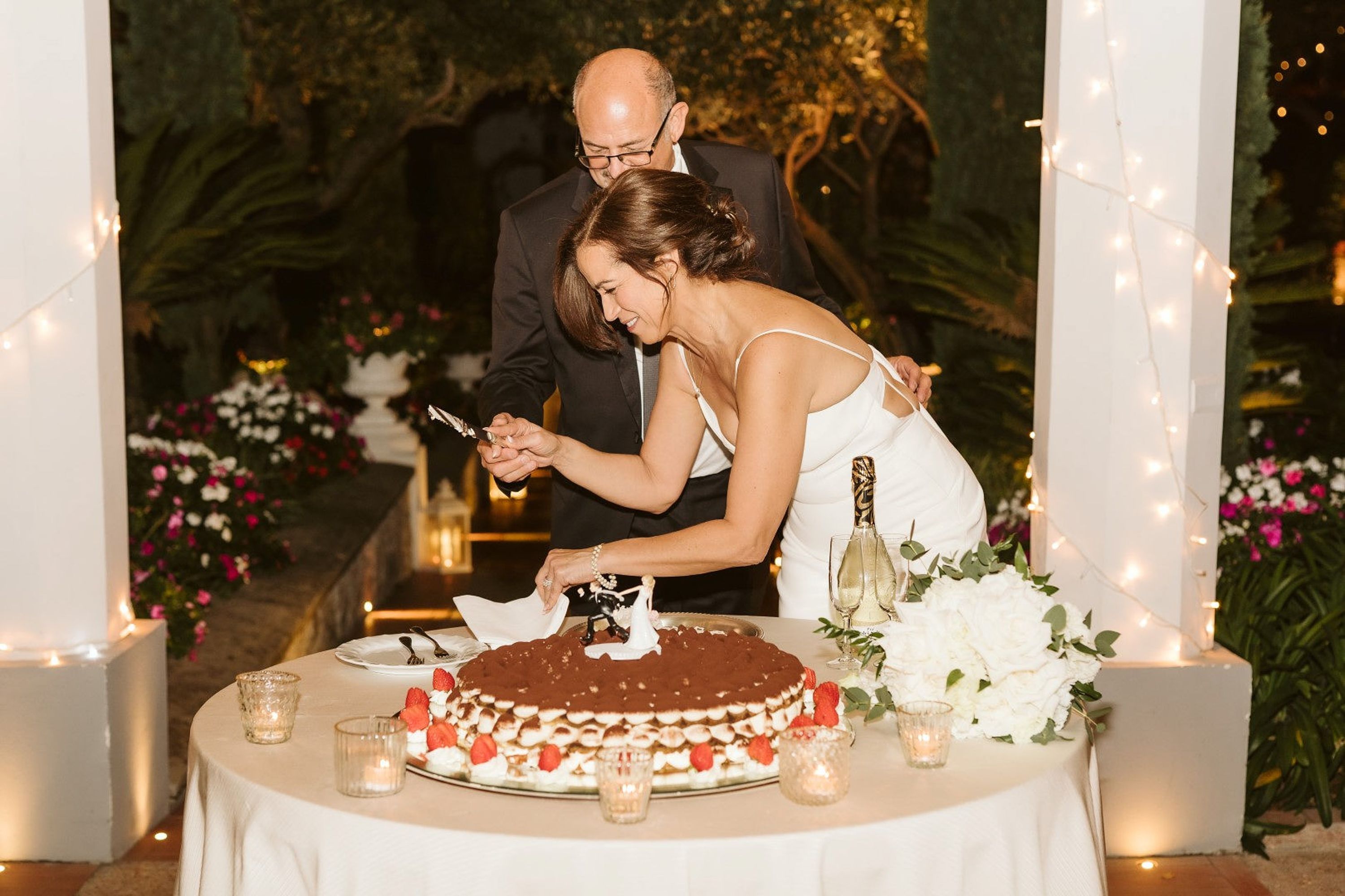 Bride and groom cut a wedding cake by candlelight during an intimate wedding in Italy reception