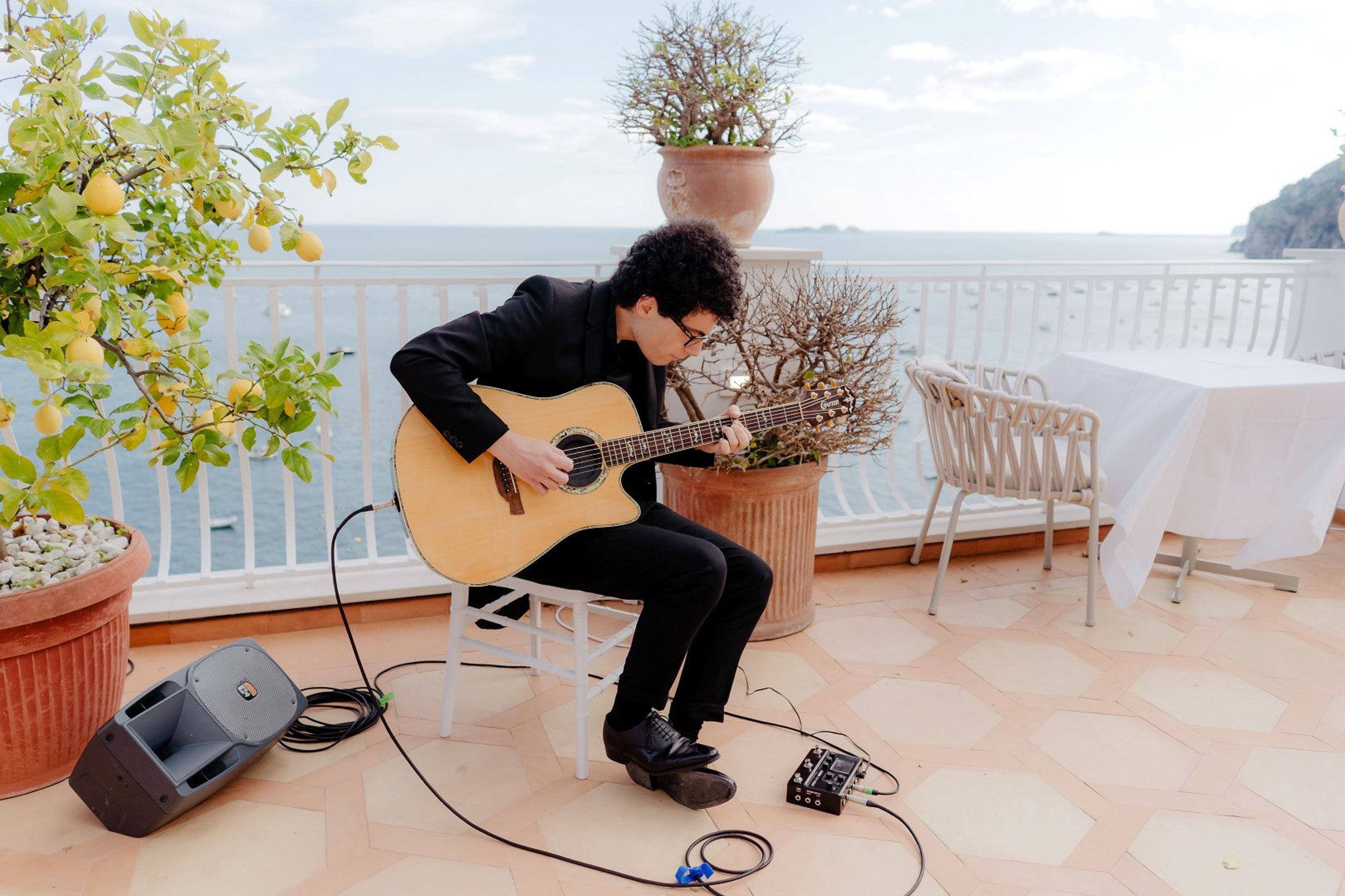 A musician strumming his guitar with a view overlooking the coast during a small wedding in Italy
