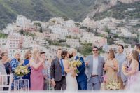 Young couple at a balcony with Amalfi coast buildings in the background during a small wedding in Italy.