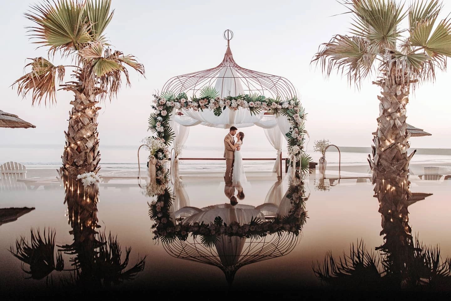 Couple looking at each other under a gazebo in the middle of a white-sand beach in Portugal