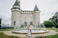 Couple holding hands and looking at each other with a big tree in the background at a vow renewal in France.