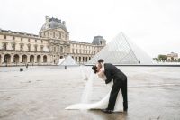 Bride and groom kissing in front of the Louvre at their wedding in Paris