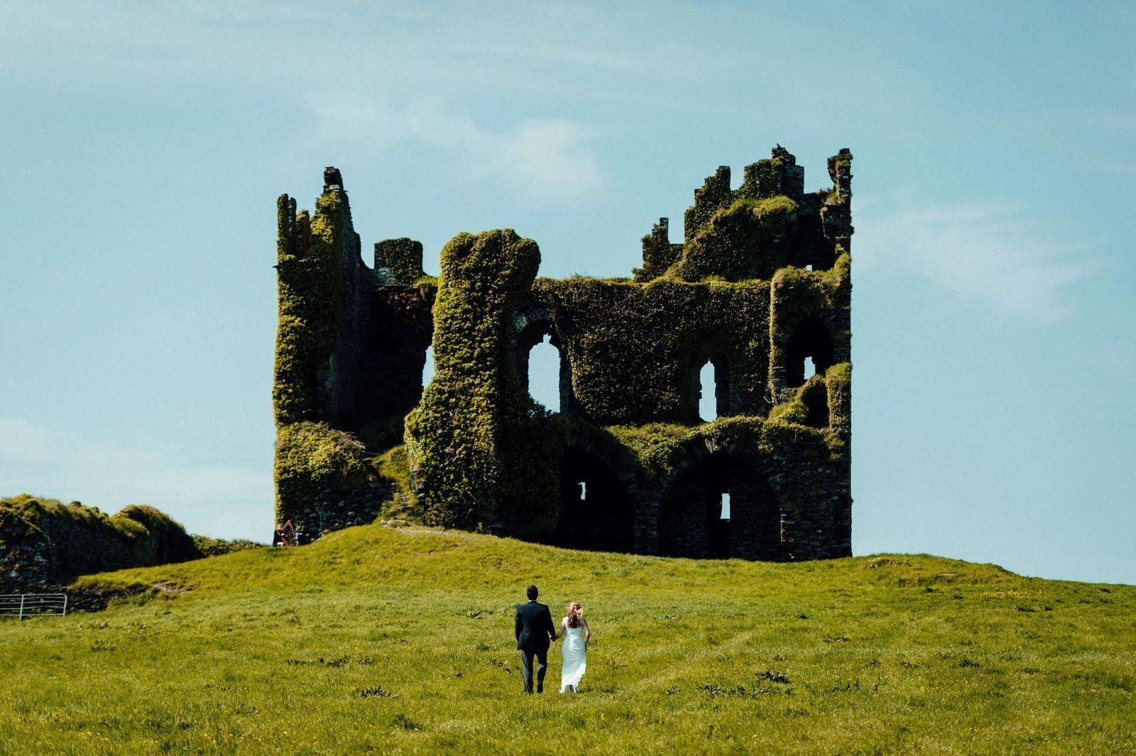 Couple walking towards a castle ruin in Ireland for their elopement