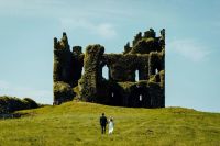 Couple walking towards a castle ruin in Ireland for their elopement