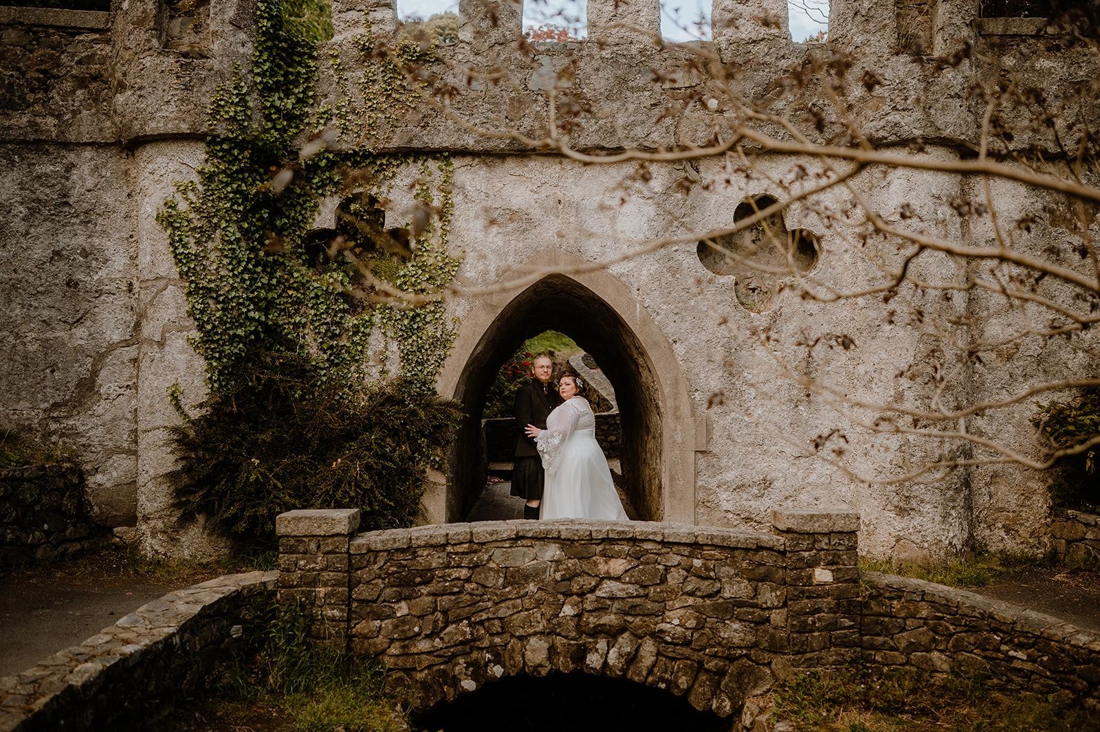 Newlyweds in front of a castle's entrance atop a small bridge in Northern Ireland